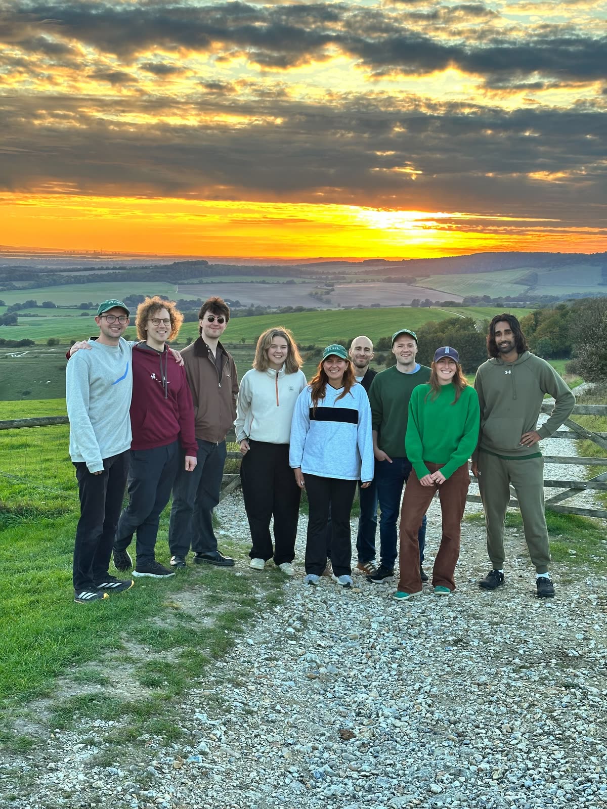 The Plinth team standing on a hillside path as the sun sets over the countryside